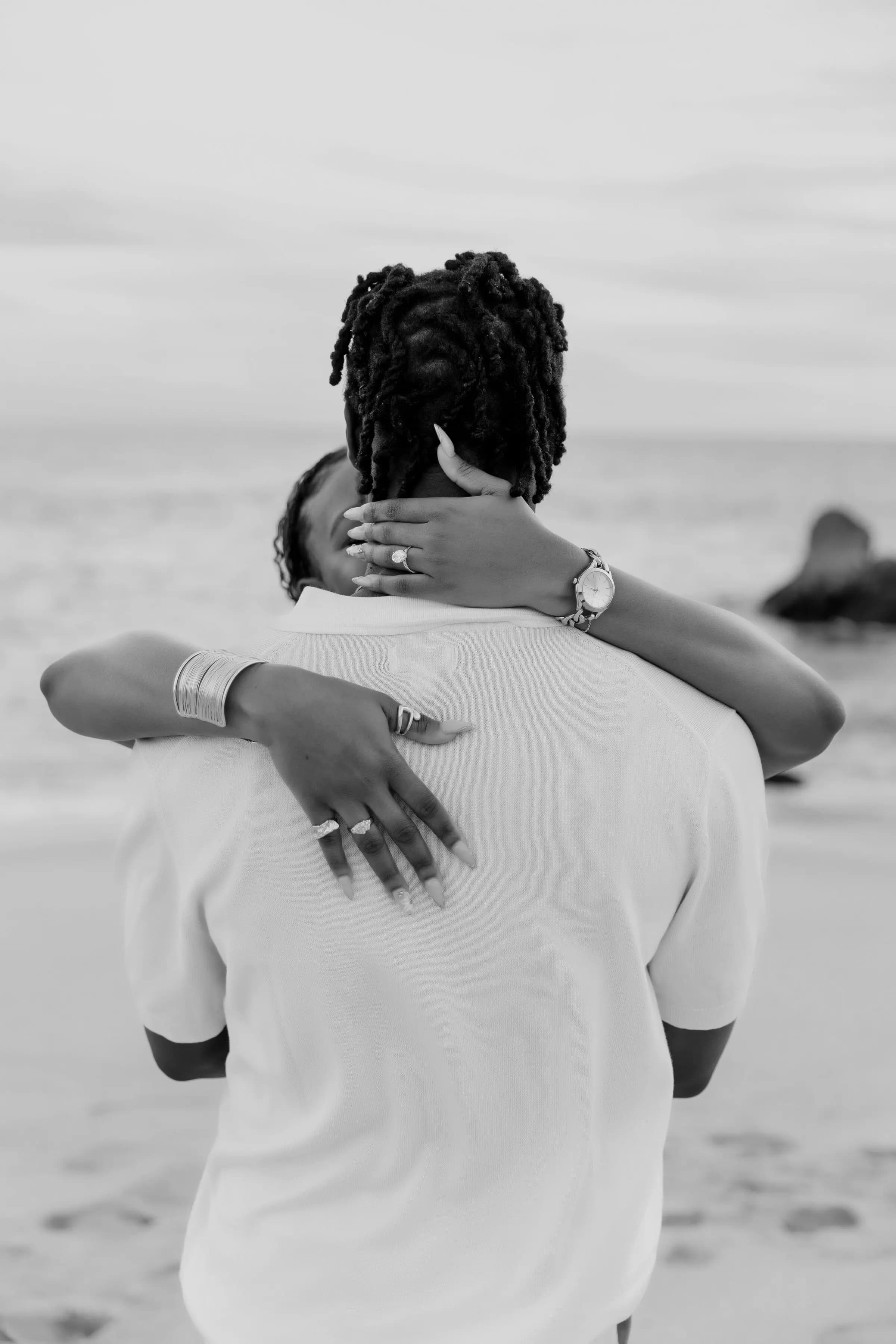 Temiloluwa and Olugbenga walking along the shore at sunset, black and white