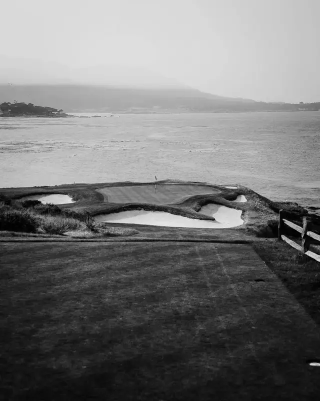 Rolling green course beside the water, black and white