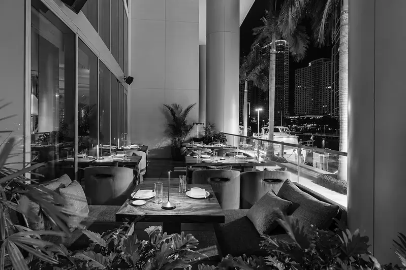 Restaurant terrace set for dinner at night, black and white